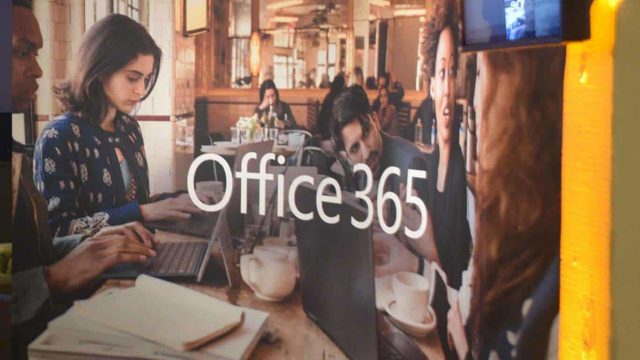 Image of reflection on glass showing people working with Microsoft devices with "Office 365" text