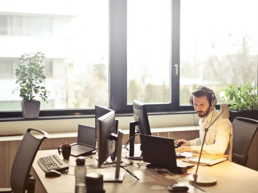 man seated on desk using emoji on PC