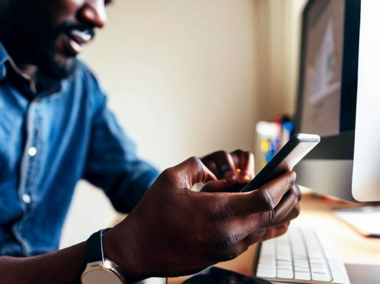 a man using his phone wile on his desktop iMessage